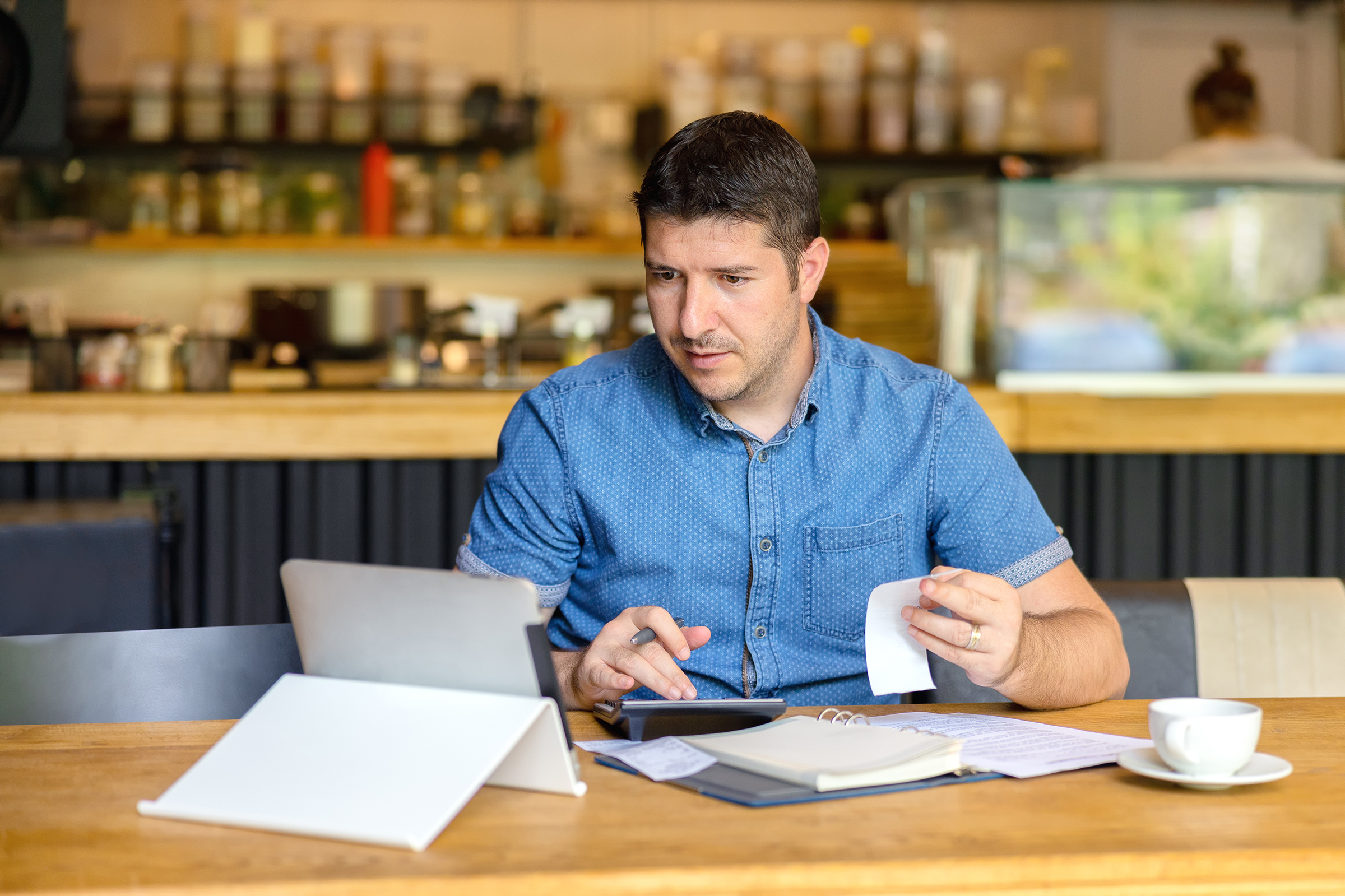 Male restaurant owner calculating finances and bills in business.