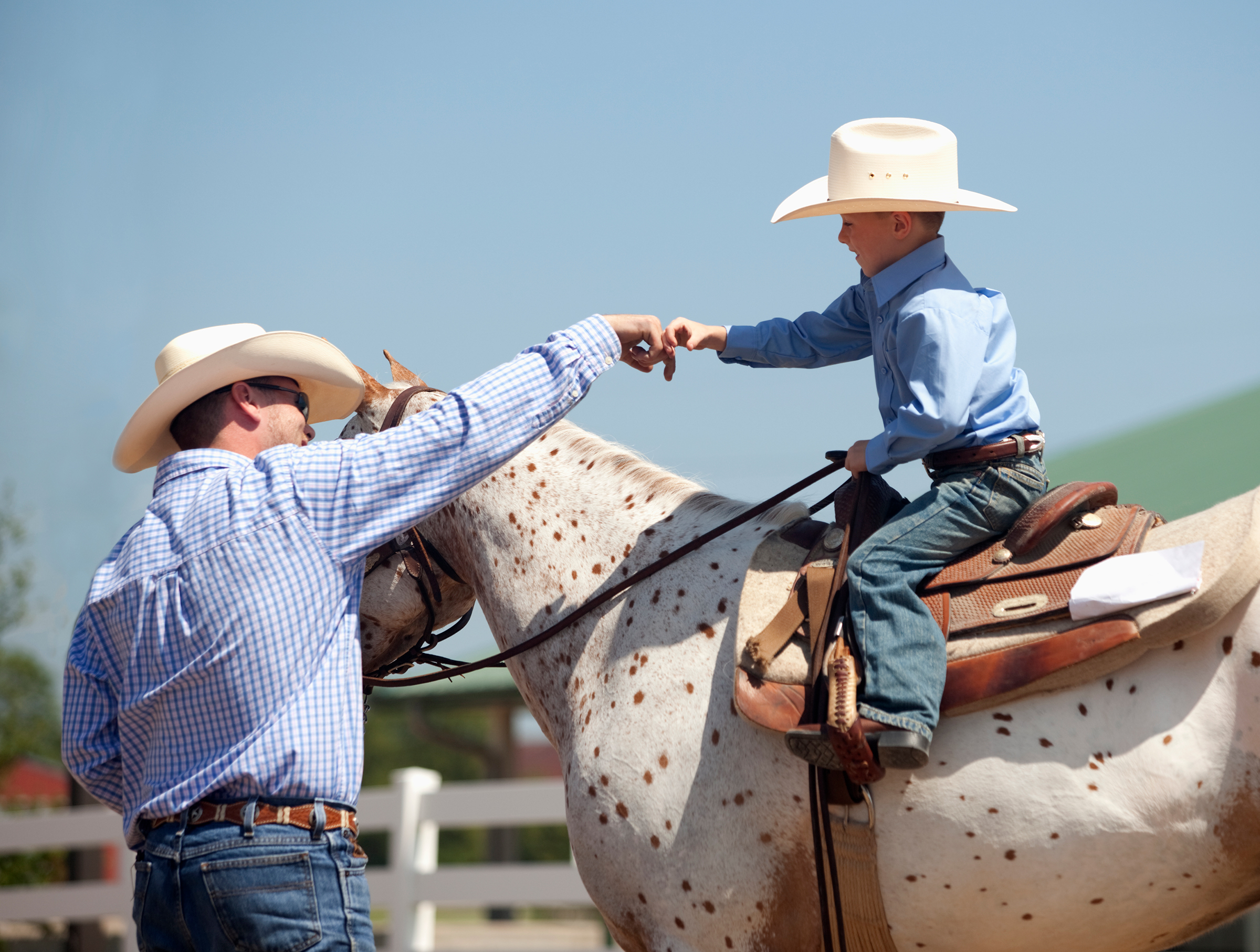 Father fist bumping son on horse