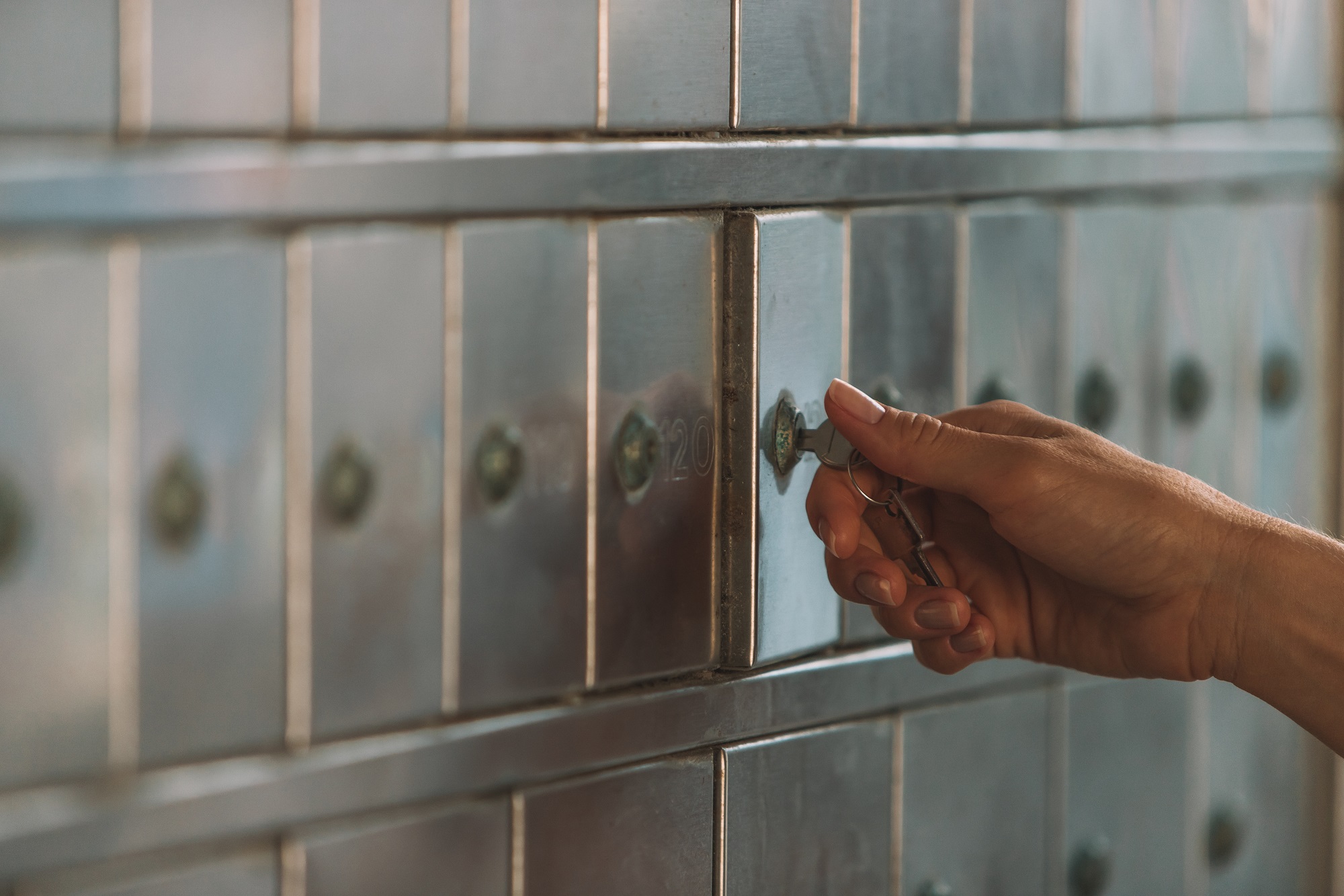 Hand turning a key to open a safe deposit box