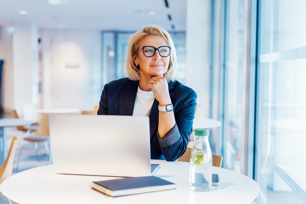 woman working on a laptop staring off into the distance