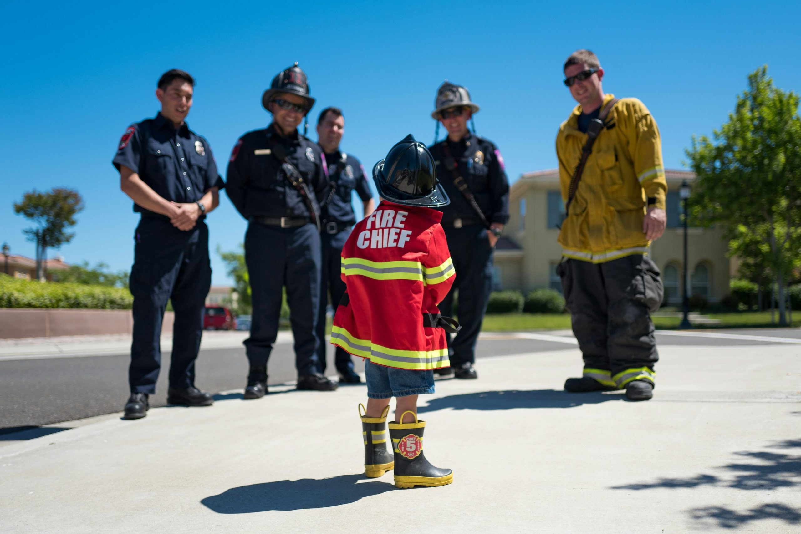 Group of firefighters talking to a child in a Fire Chief jacket